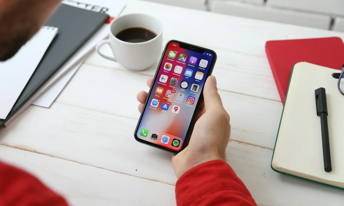 Človek používa mobilný telefón pri pracovnom stole